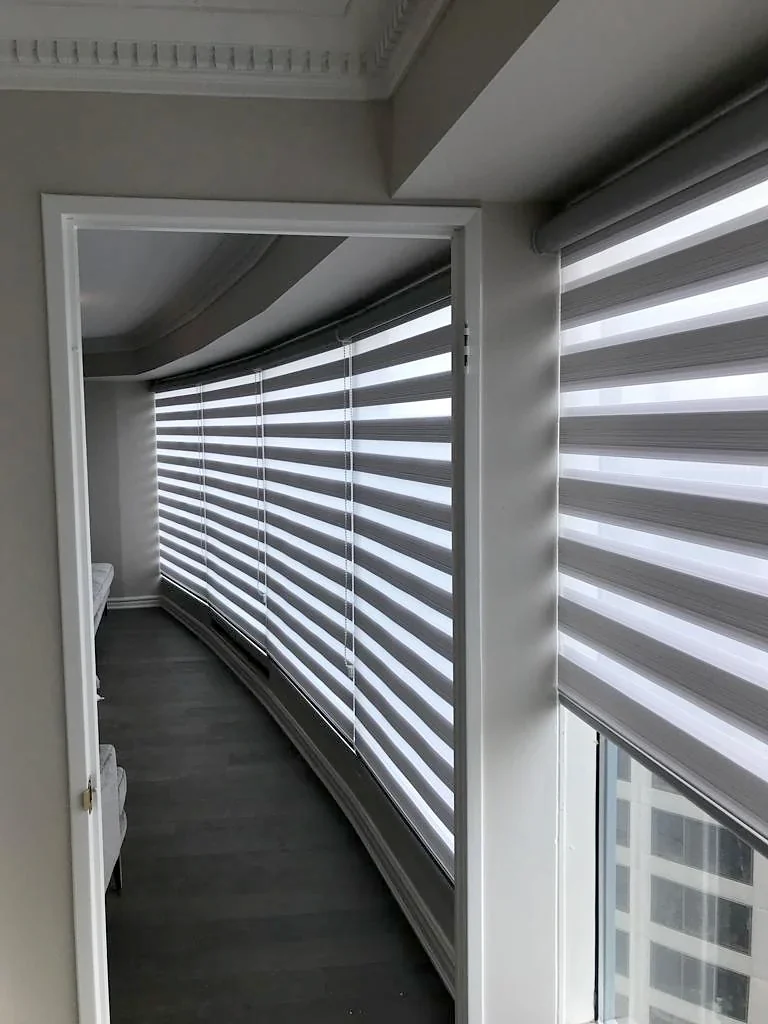 Zebra shades following a curved wall of glass in a high-rise flat, one to each pane